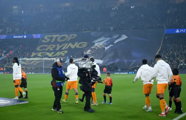 Madrid players make their way out onto the pitch faced with the big Rodri banner