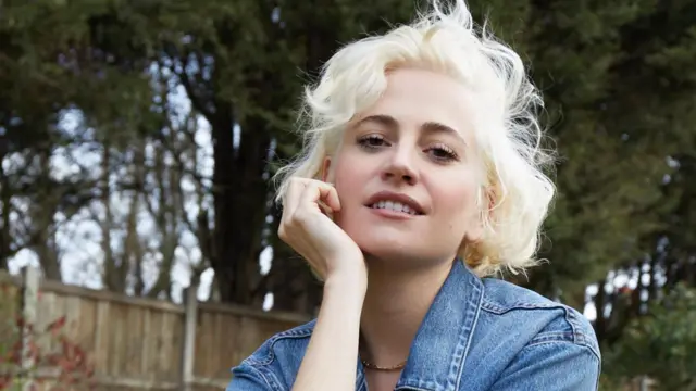 Pixie Lott seen in a publicity image, wearing a denim shirt and photographed outside in a garden