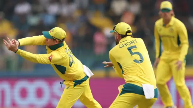 Australian fielders attempt to stop the ball