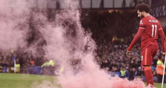 Mo Salah celebrates after scoring as a red flare is thrown onto the pitch