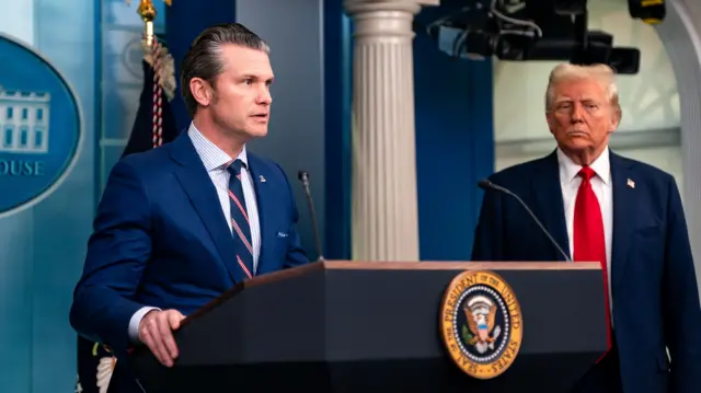 Trump and Hegseth stand at a podium in the white house briefing room.