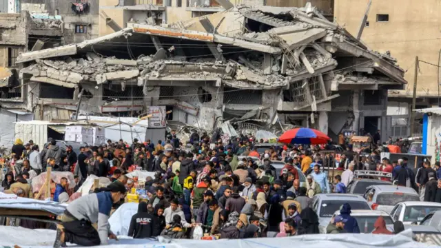 Palestinian residents, shopping at the market, try to meet their basic needs among the collapsed buildings as they continue to live in Khan Yunis, Gaza, which was heavily damaged by Israeli airstrikes before their withdrawal, on February 12, 2025