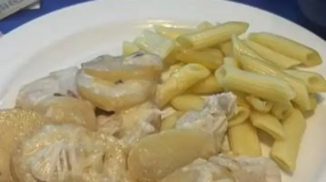 A plate of potatoes and pasta. It looks plain and unappetising. There is a white thick sauce over the potatoes with chunks in