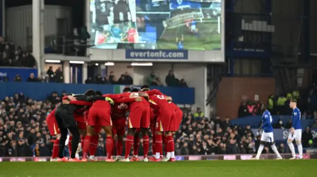 Liverpool players huddle together on the pitch