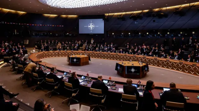 Wide shot of large round table with people sat around it