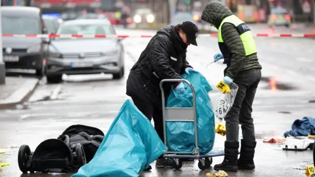 Two police officers gather evidence after some 28 people were hurt when a car drove into a group in Munich