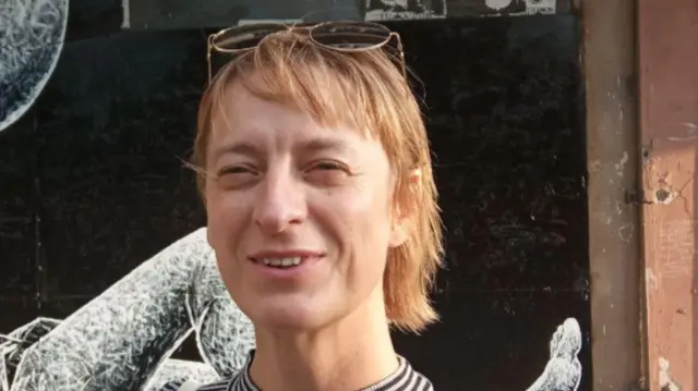 A woman smiles with sunglasses on her head.