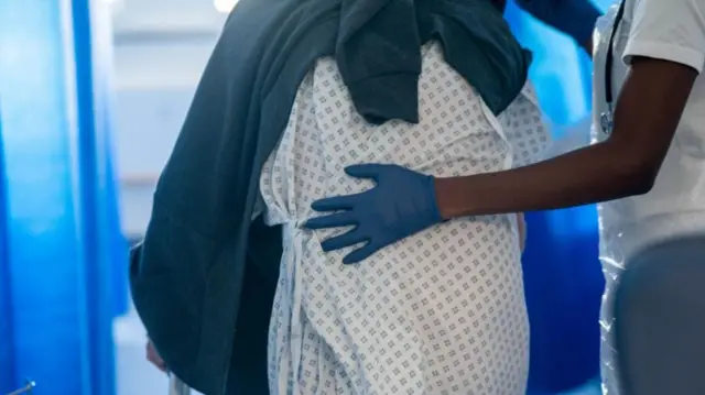 Doctor helps hospital patient walk by supporting her back