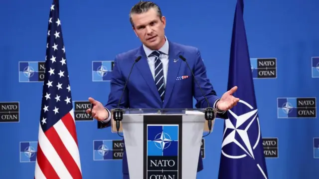 Hegseth speaks from a podium featuring word 'Nato'