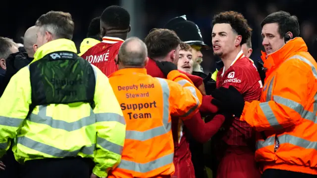 Liverpool's Curtis Jones and Everton's Abdoulaye Doucoure are separated by team-mates and members of the ground staff