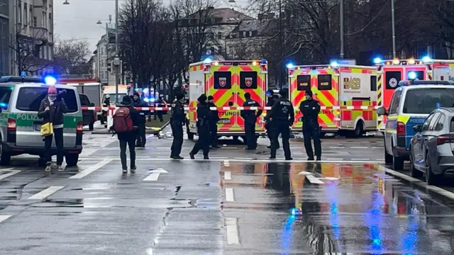 Police and ambulances stand behind a cordon