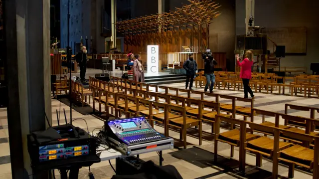 A behind-the-scene look at Coventry Cathedral with a reporter doing a piece to camera and sound equipment in the foreground