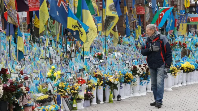 A man gestures as he walk past a makeshift memorial to the fallen Ukrainian servicemen and international volunteers, in Independence Square in Kyiv, Ukraine,