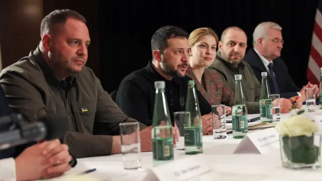 Zelensky sits at a table, flanked by Ukrainian officials