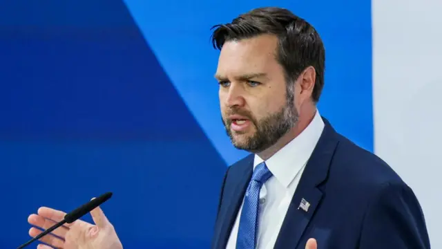 JD Vance giving a speech in front of a blue background