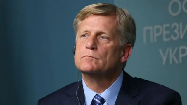 Michael McFaul looks off into the distance; he has an earpiece attached to him.