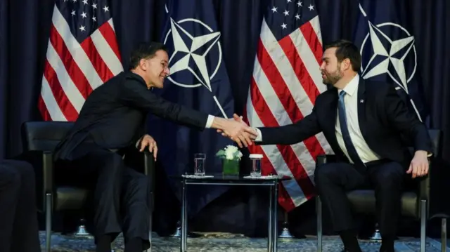 Nato Secretary General Mark Rutte and US Vice President JD Vance shake hands while sitting down in front of US and Nato flags