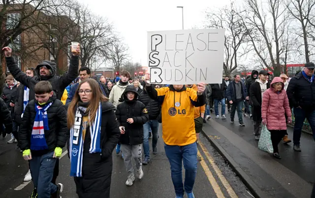 A fan holds up a sign which reads "Please Sack Rudkin" during a organised protest