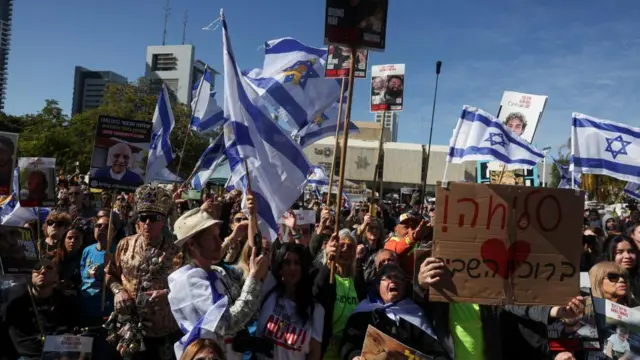 People react as they watch news coverage from hostages square.