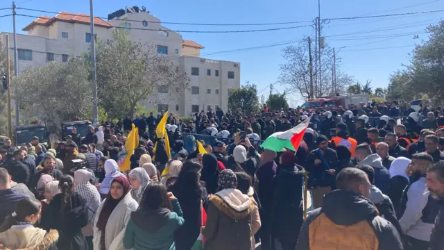 A crowd has gathered in Ramallah under a blue sky.