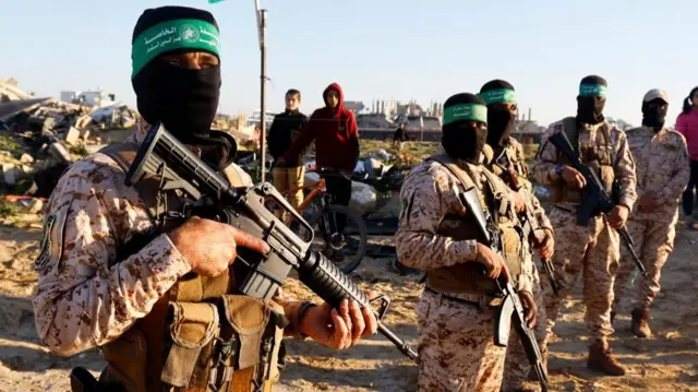 Masked Hamas gunmen stand guard before the release of hostages held in Gaza