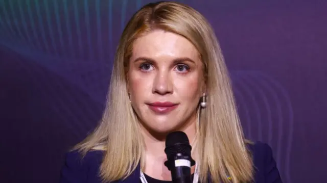 Ukraine MP Kira Rudyk speaking with a microphone in front of a purple background