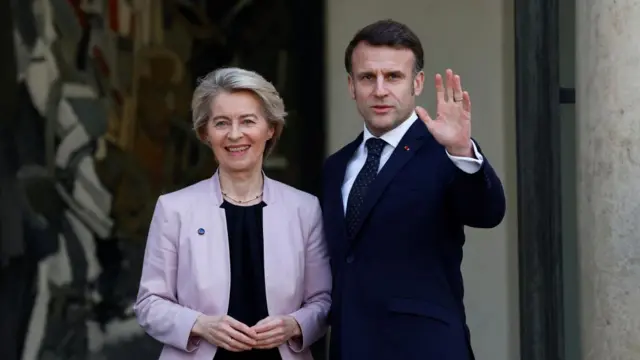 Macron waves standing next to Ursula von der Leyen