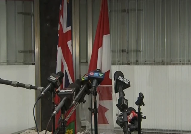 Microphones visible in front of a Union flag and Canadian flag