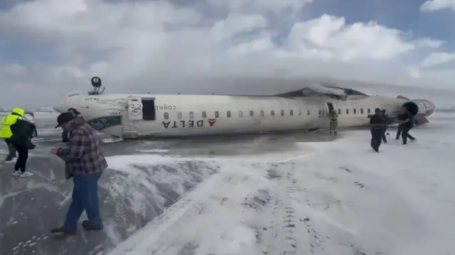 A plane upside down on a runway that is covered in snow.