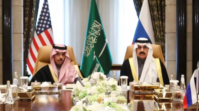 The Saudi hosts sit at a wooden table