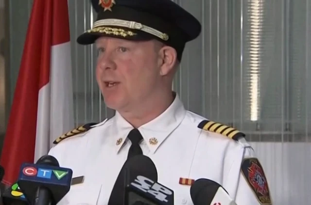 Fire Chief Todd Aitken standing in front of a podium with microphones on it