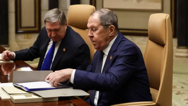 The Russian delegation sit at a wooden table