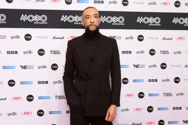 A close up of DJ Target smiling on the red carpet.