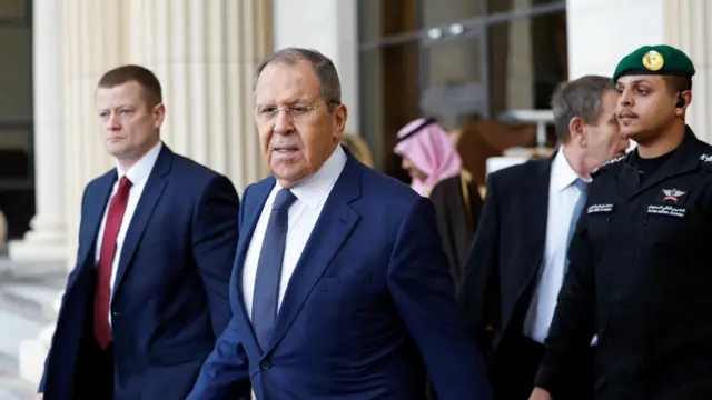 Lavrov leaves his hotel, surrounded by other men in suits