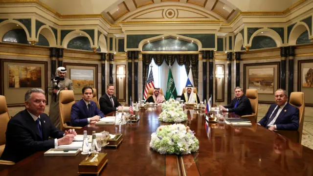 The Russian and US delegations sit around a wooden table