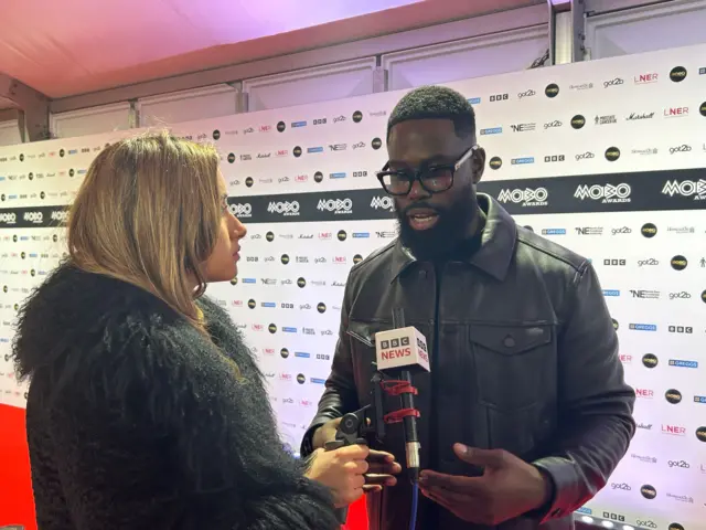 Lola Schroer and Ghetts speaking on the red carpet