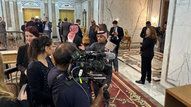 A marble room filled with officials and reporters