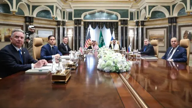 US and Russian delegations around large wooden table in Saudi