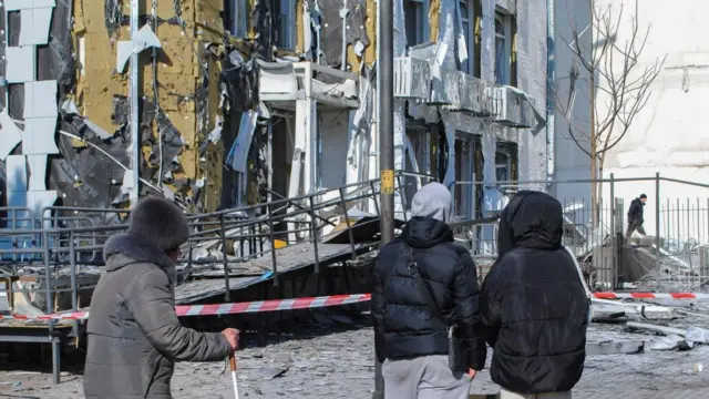 Three people stand in front of a damaged children's clinic