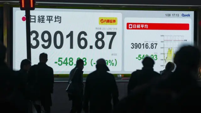 An electronic stock board displays numbers with silhouettes of people in front
