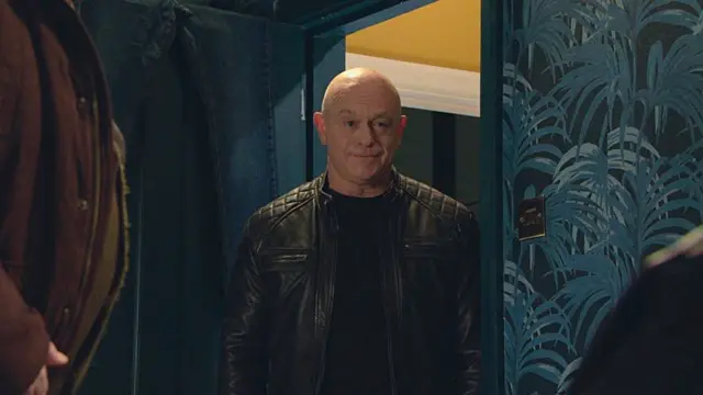 Still of EastEnders character Grant Mitchell, played by Ross Kemp, standing in a doorway with the partial view of another man on the left