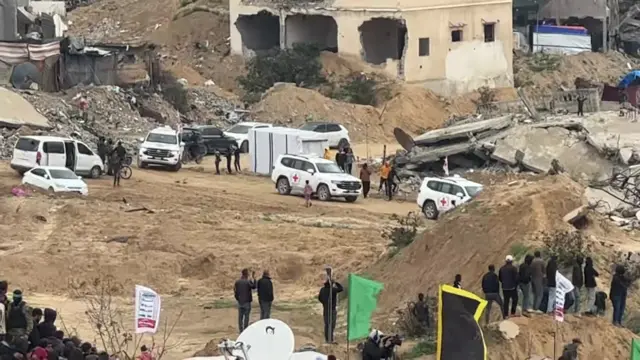 Several Red Cross vehicles drive down a slope