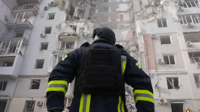 An emergency services worker stands in front of a building hit by an airstrike in Kherson