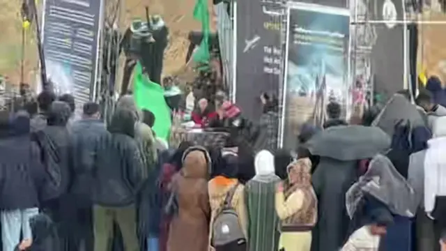 A Red Cross worker and a member of Hamas sign a document on stage