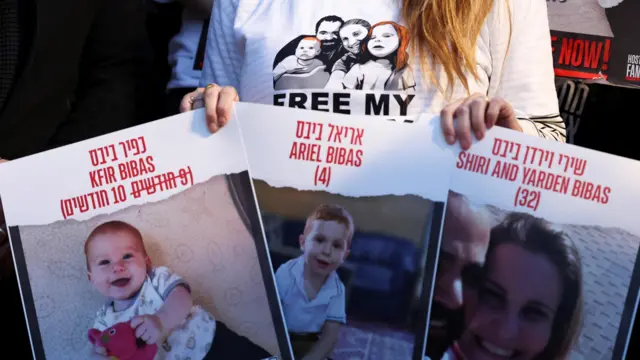 A protester holds signs of Shiri Bibas, 32, and her children Kfir Bibas, 10 months, and Ariel, four