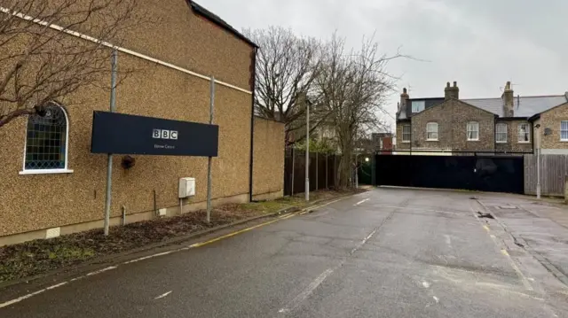 Streetscape outside EastEnders set with a black sign with the BBC logo on the left side