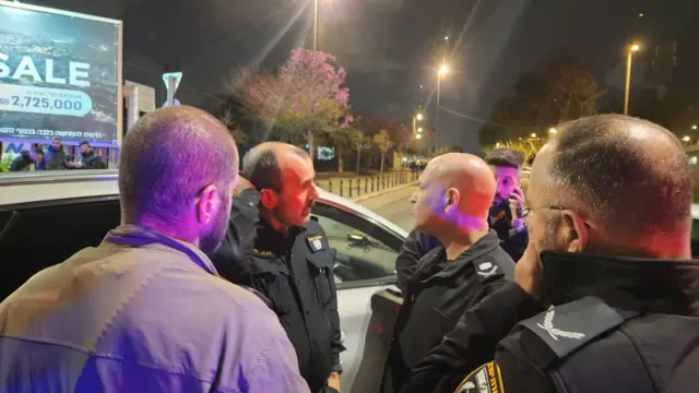 Police stand outside car in the dark