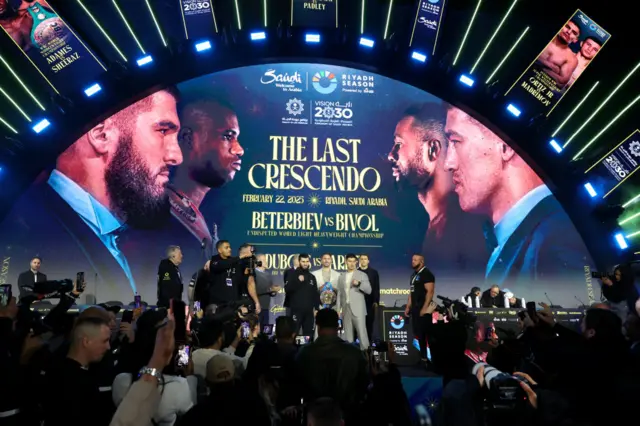 A long shot of Artur Beterbiev and Dmitry Bivol posing alongside each other for pictures at a news conference