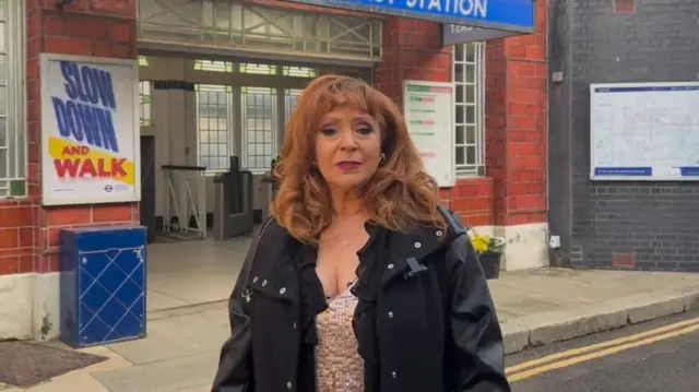 Harriet Thorpe standing in front of the fictional Walford East tube station on the Eastenders set