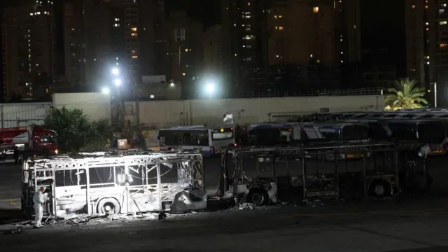 Buses burnt out on a street at night.